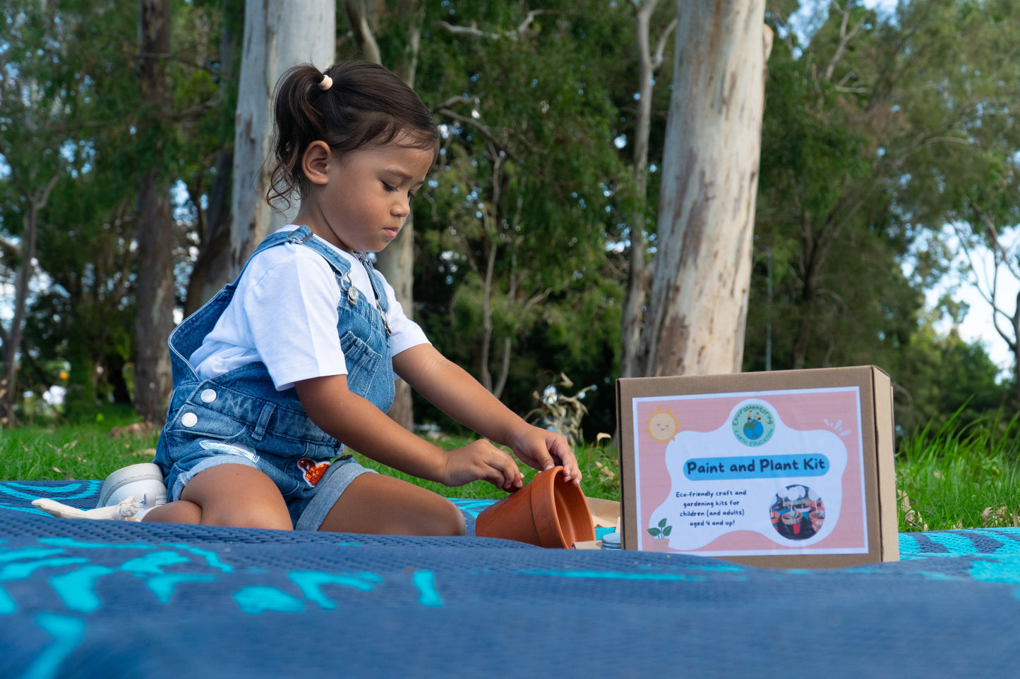 A young is focused as she colours her terracotta pot with eco-friendly crayon rocks in her EnviroMentoring Paint and Plant DIY Kit.