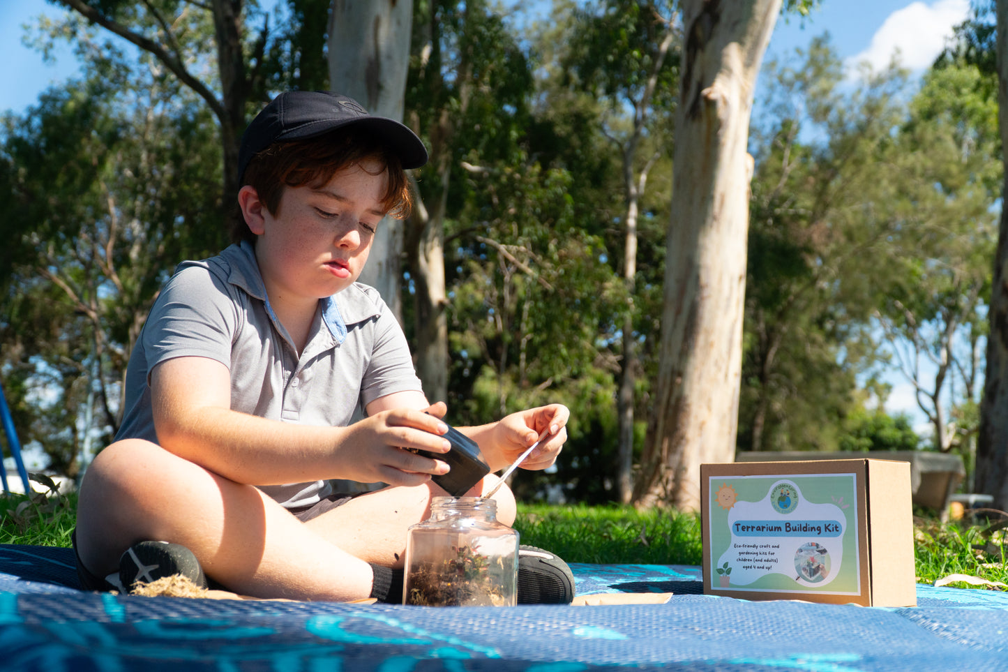 A boy pours soil into his terrarium from his EnviroMentoring Terrarium Building DIY kit.