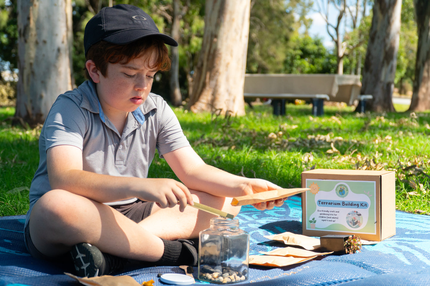 A boy using bamboo tweezers to place his horticultural charcoal into his terrarium from the EnviroMentoring Terrarium Building DIY kit.
