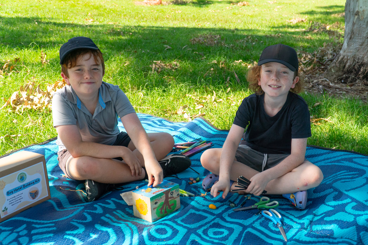 Two young boys smile ta the camera while decorating their EnviroMentoring Bug Hotel DIY Kit.
