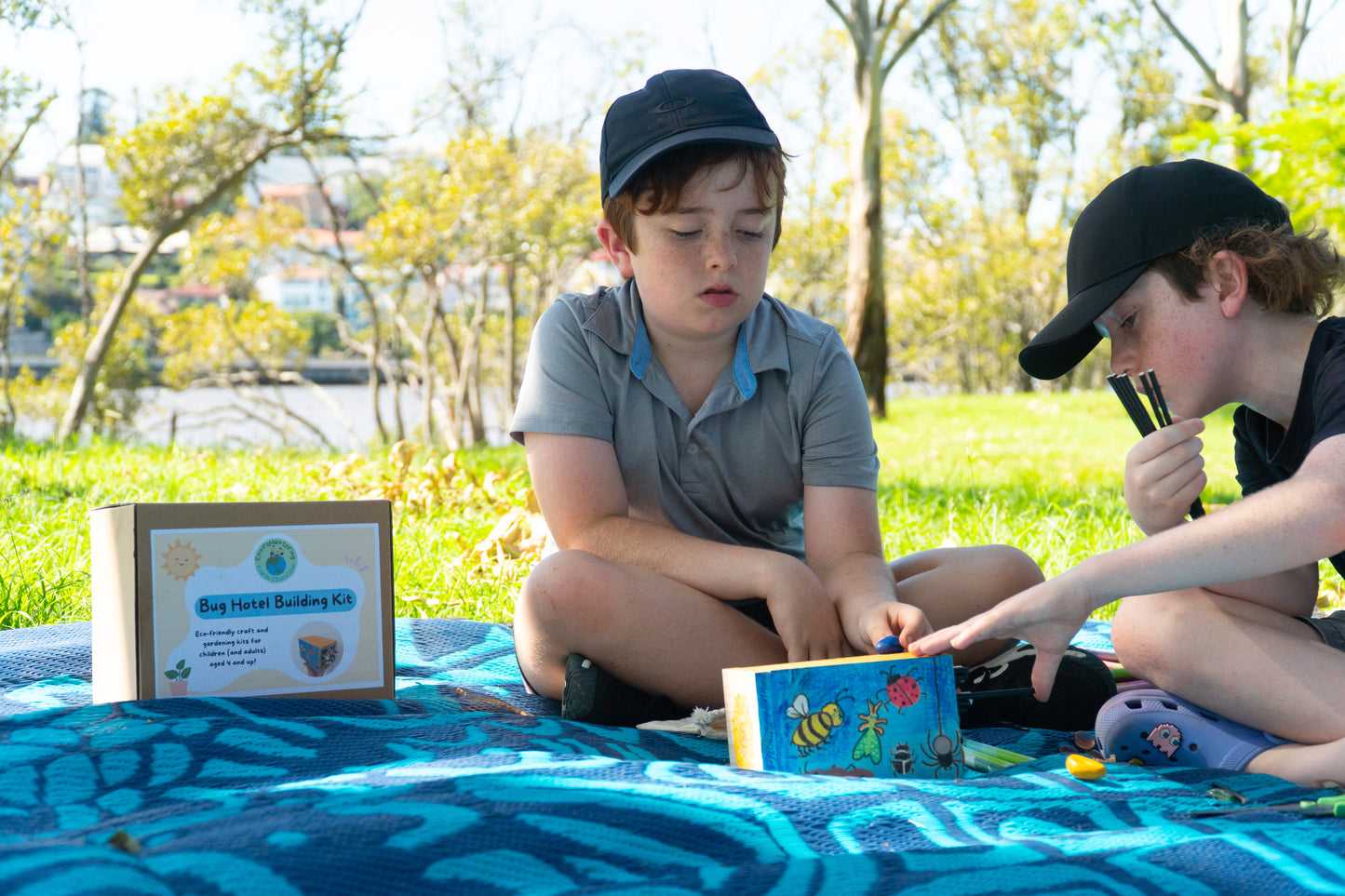 Two young boys decorate their EnviroMentoring Bug Hotel DIY Kit with rock crayons and fill them with straws and bamboo.