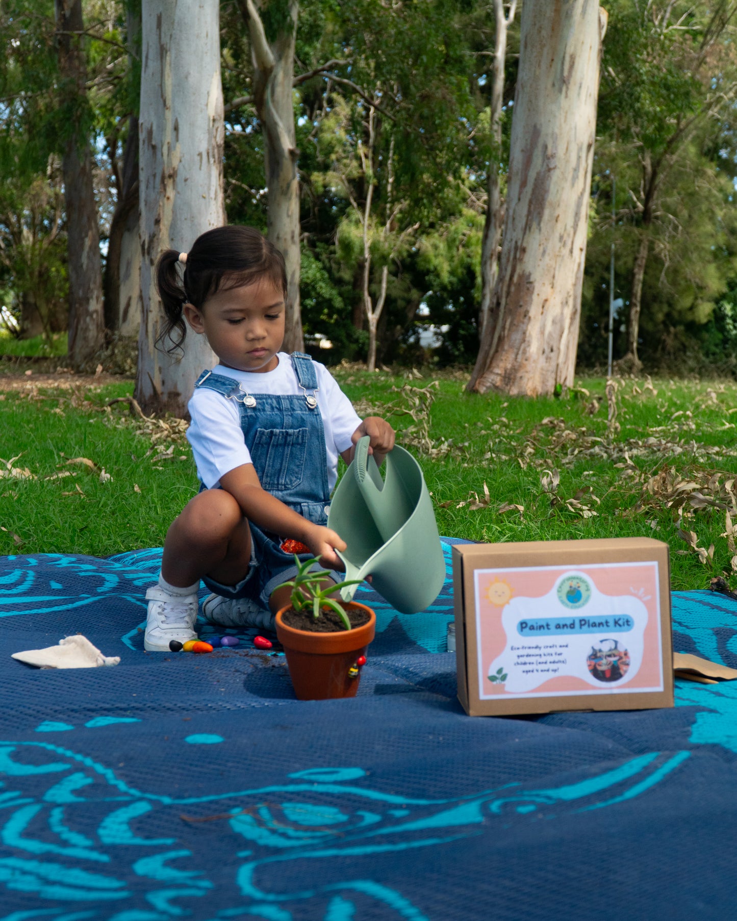 A young girl waters her decorated terracotta pot from her EnviroMentoring Paint and Plant DIY kit.