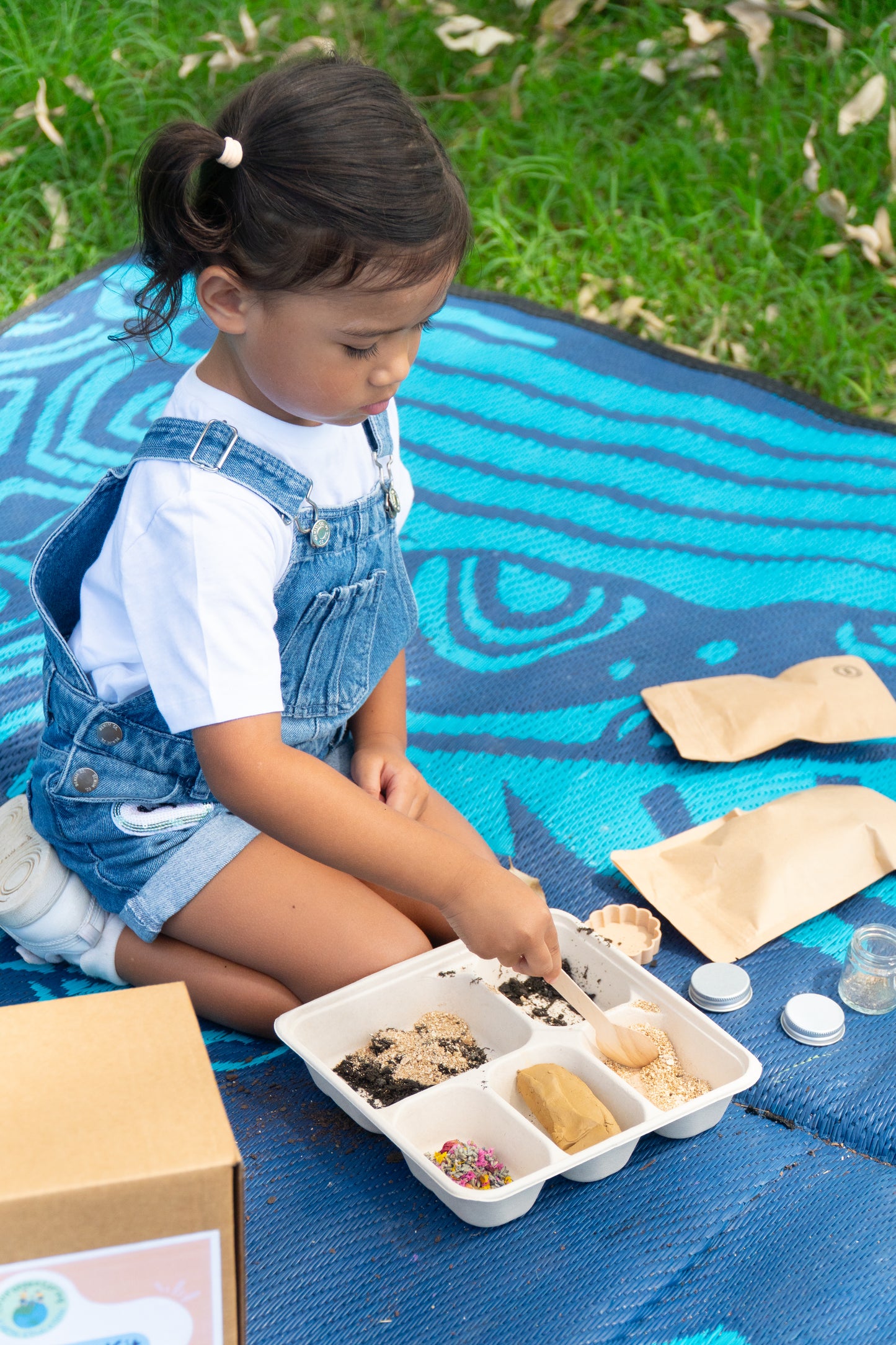 A young girl is scooping seeds into her tray to make her EnviroMentoring Seed Surprise DIY Kit.