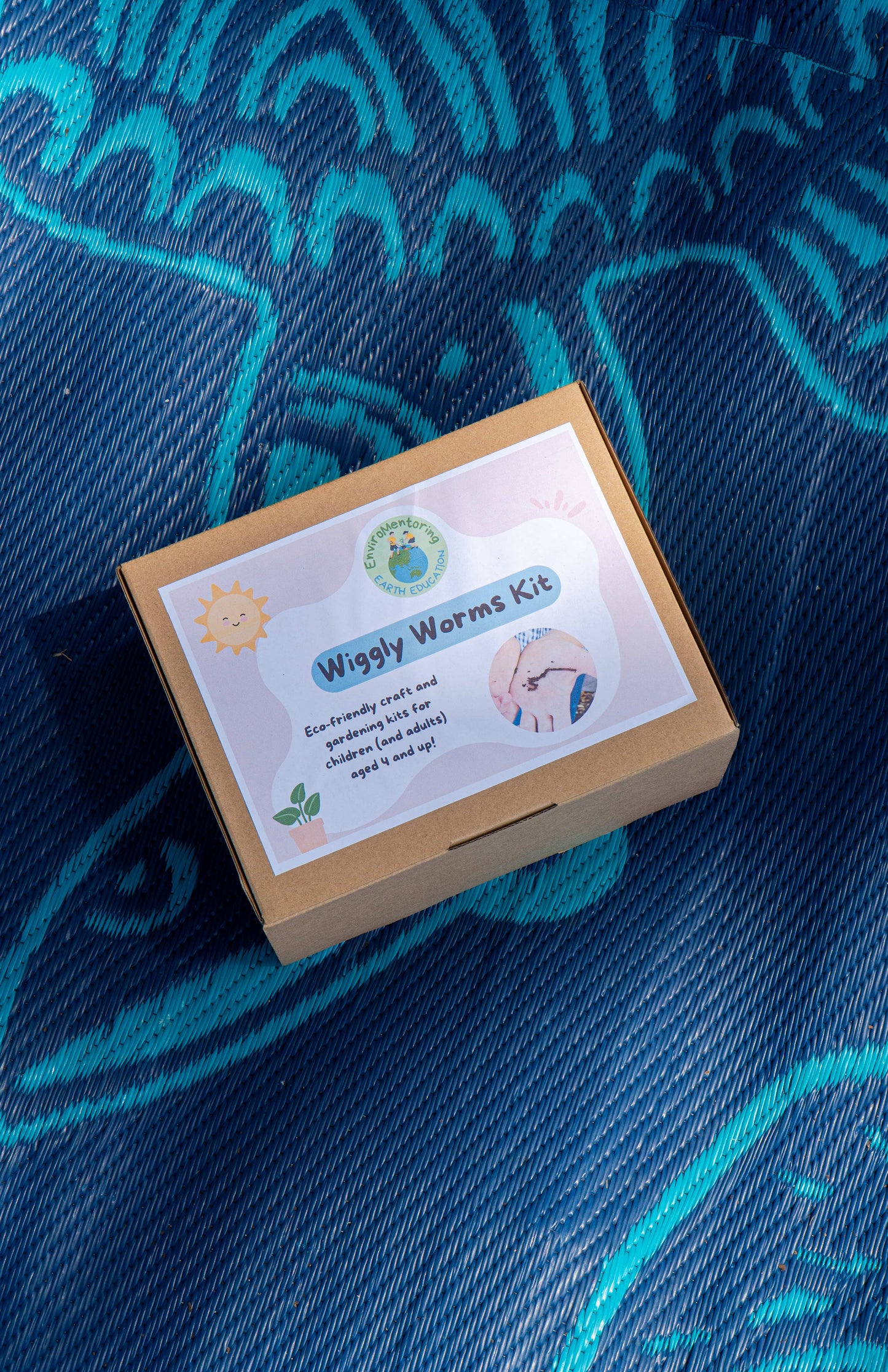 Image of the EnviroMentoring Wiggly Worms DIY Kit box on a blue recycled mat.
