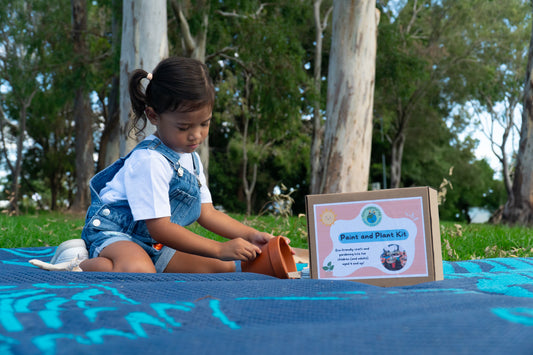 A young girl carefully colours in her terracotta pot with eco-friendly crayon rocks in her EnviroMentoring Paint and Plant DIY Kit.