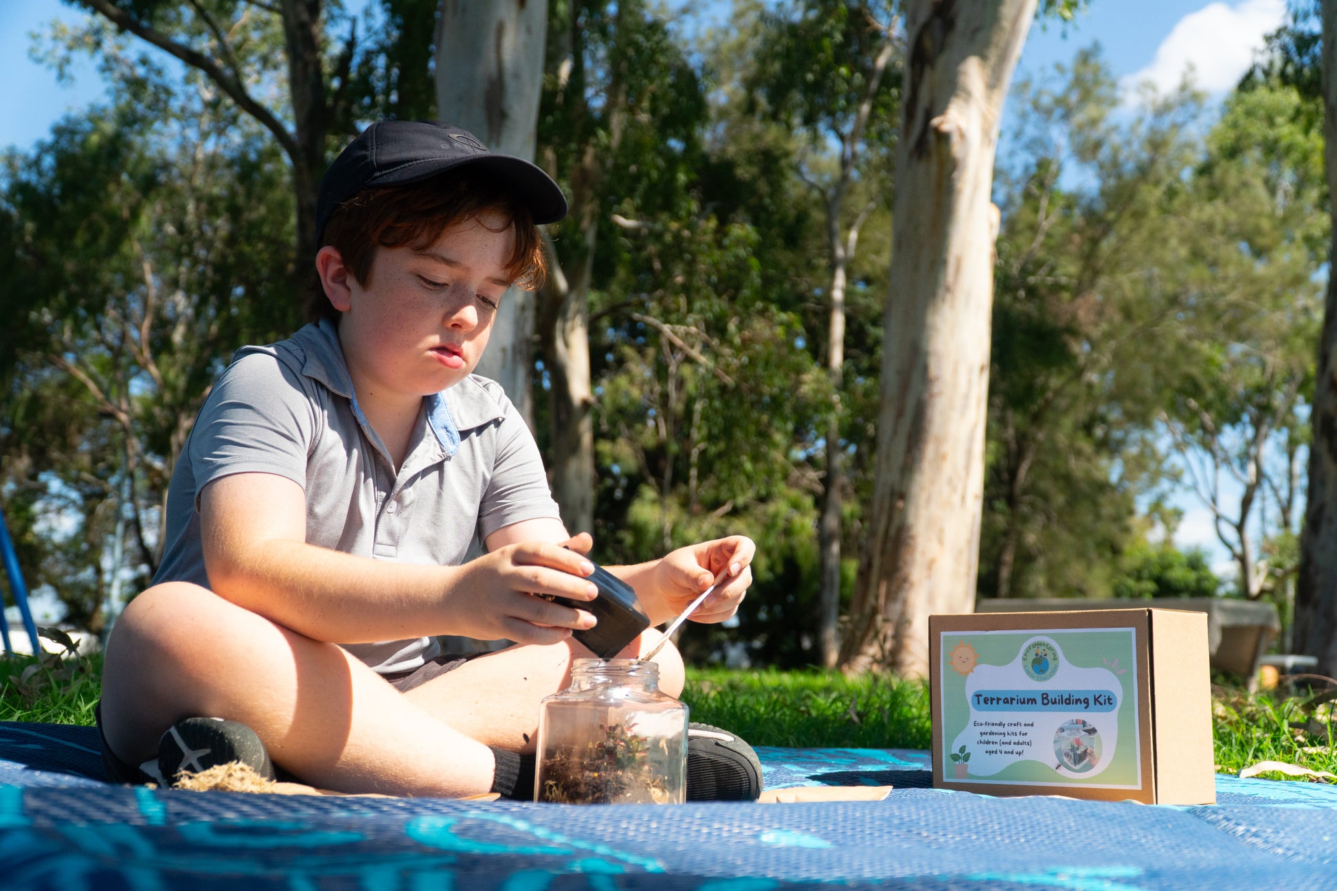 A boy pours soil into his terrarium from his EnviroMentoring Terrarium Building DIY kit.