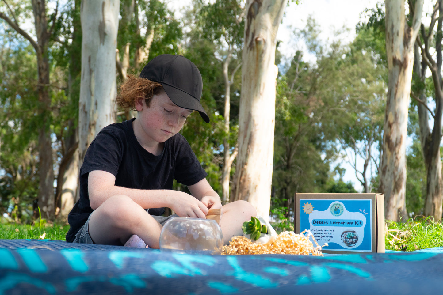 A boy opens his environmentally-friendly rock packaging for his EnviroMentoring Desert Terrarium DIY Kit.