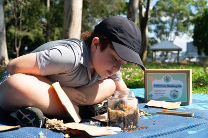 A young boy studies his completed EnviroMentoring Terrarium Building DIY Kit. 