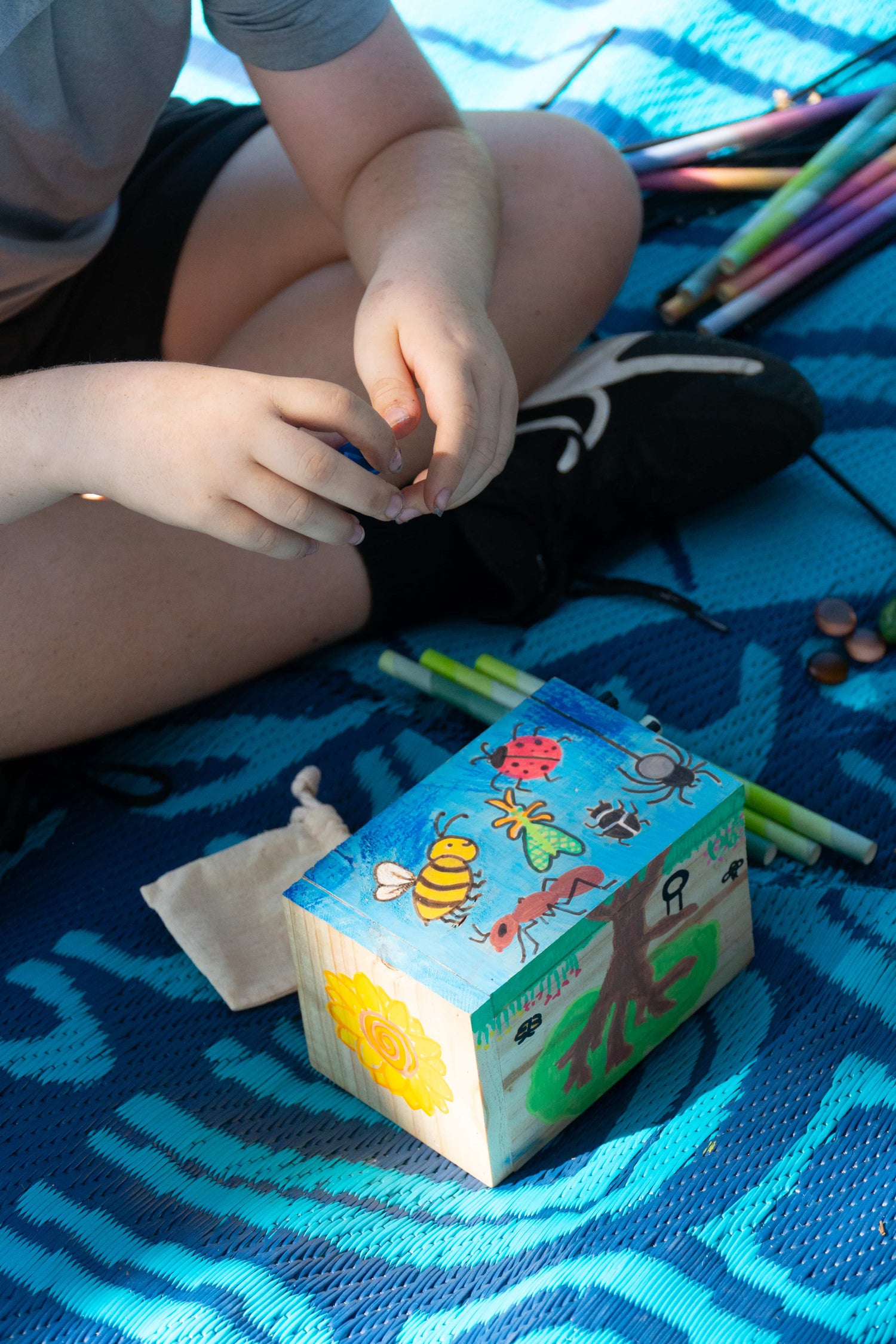 A young boy decorates his EnviroMentoring Bug Hotel DIY Kit with eco-friendly rock crayons.