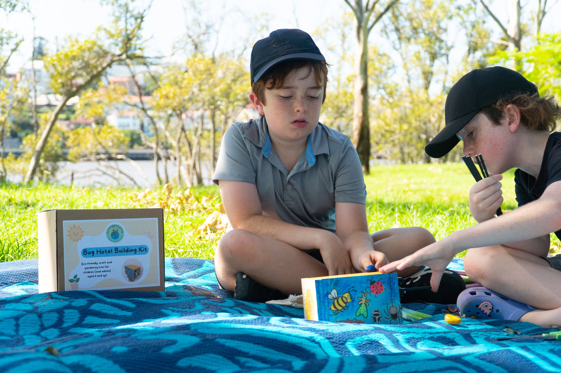 Two young boys decorate their EnviroMentoring Bug Hotel DIY Kit with rock crayons and fill them with straws and bamboo.